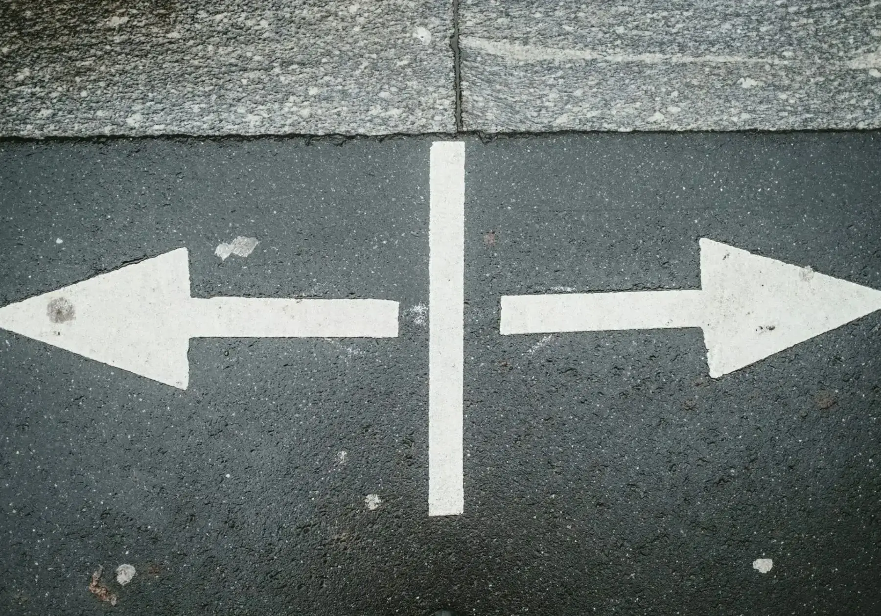 Two opposite direction arrows on pavement.