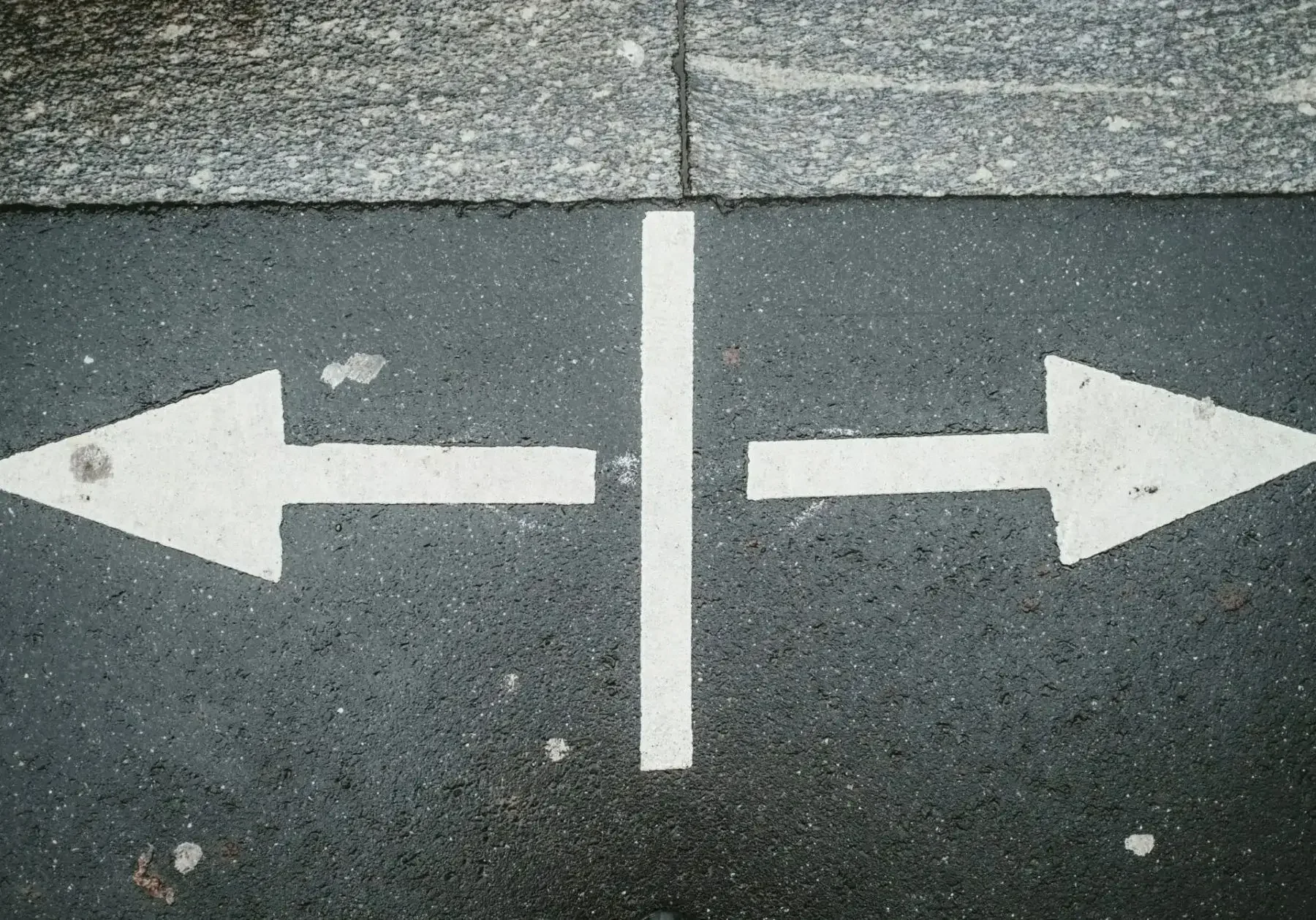 Two opposite direction arrows on pavement.